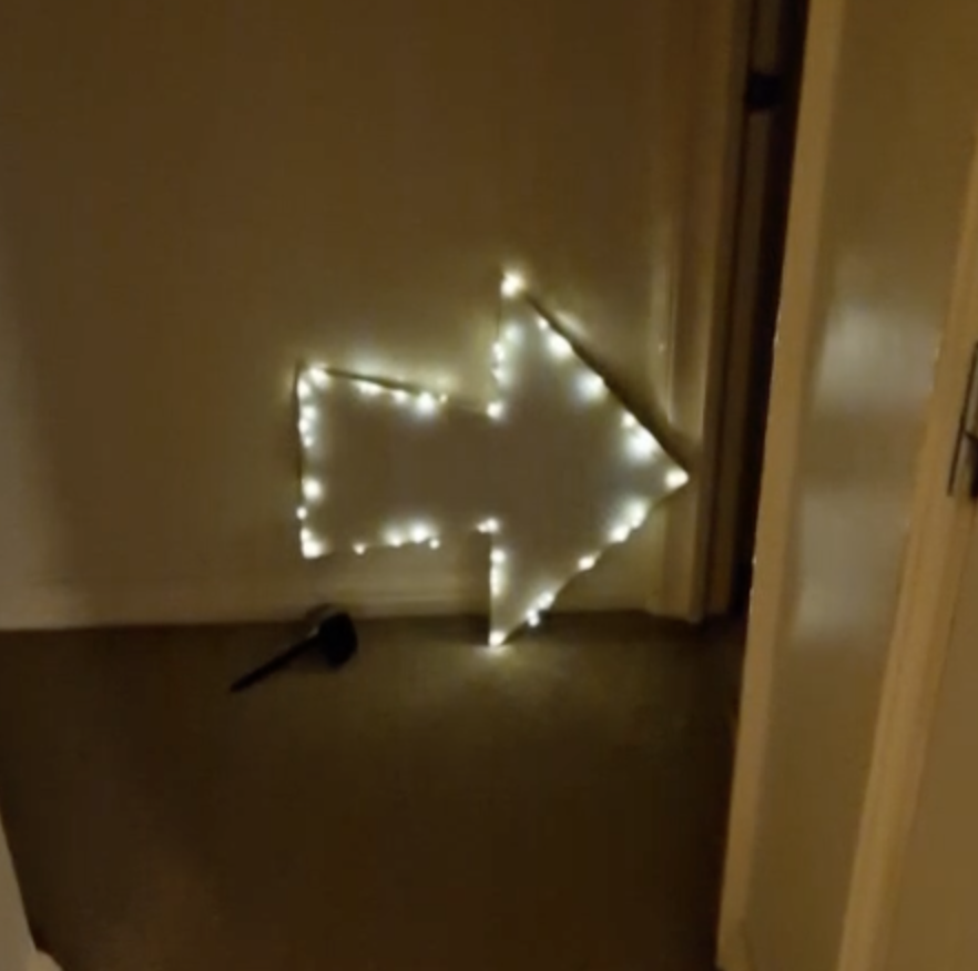 A white arrow sign with fairy lights round the edge