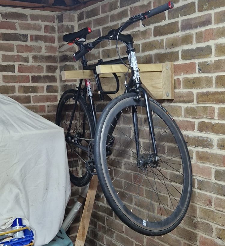 A bike hanging on a wall from a bike hanger made of scrap wood