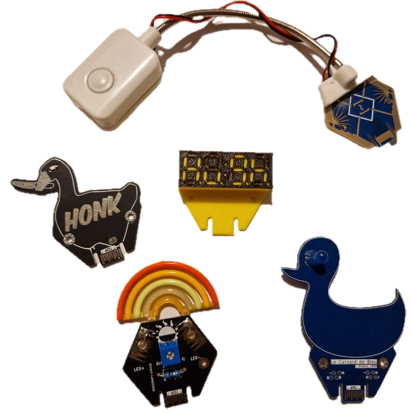 All the hexpansions I collected at EMF this year, a duck, a rainbow, a goose, a 3d printed seven segment display, and a reading light